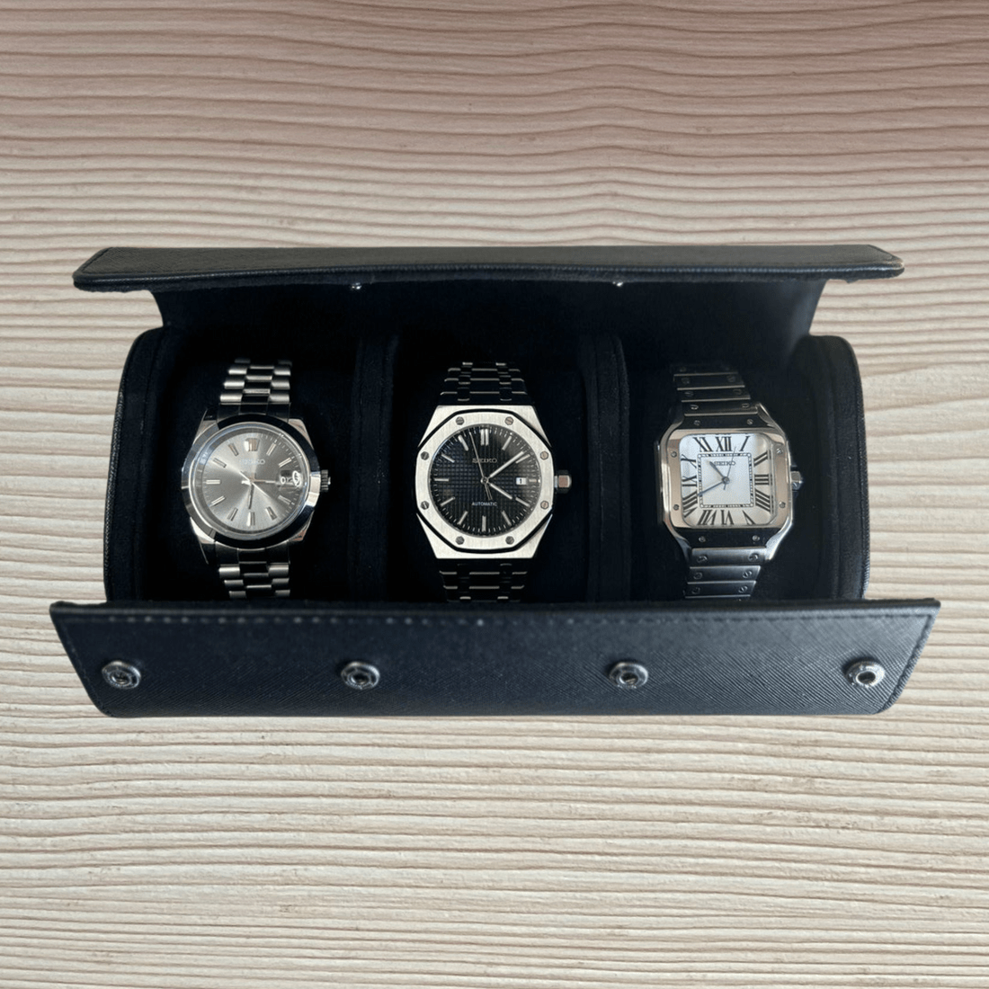 Étui de voyage noir ModTime pour trois montres, trois montres dans des compartiments séparés, vue ouverte sur du bois