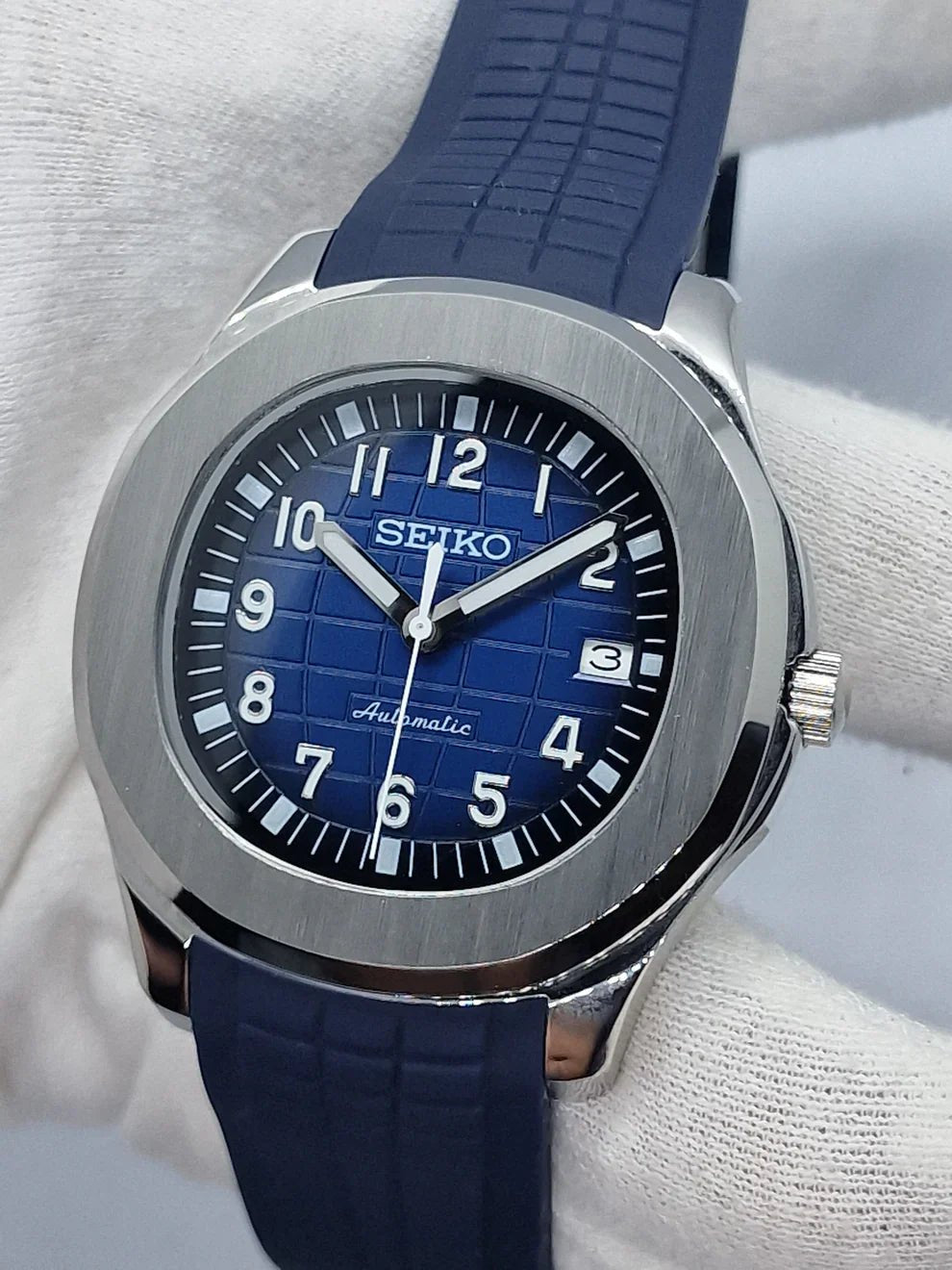 Montre automatique ModTime de style Aquanaut — configuration bleue (NH35), cadran bleu, chiffres en relief, tenue dans un gant blanc