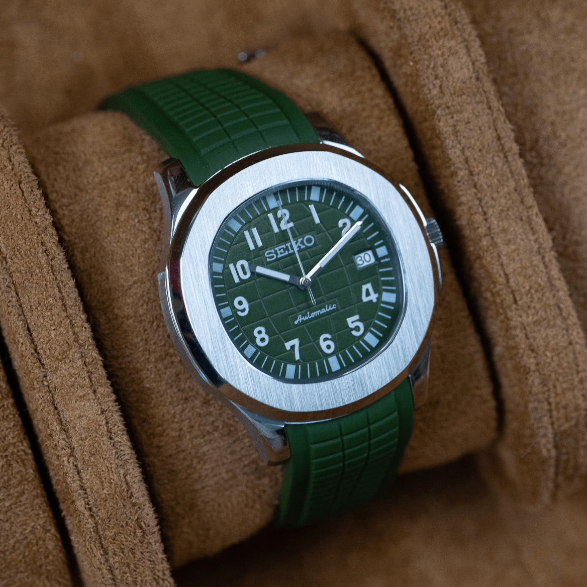 Montre automatique ModTime de style Aquanaut — configuration verte (NH35), cadran vert, chiffres en relief, vue en biais côté gauche sur un coussin