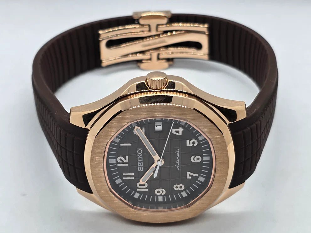 Montre automatique de style Aquanaut — configuration aux tons or rose, cadran marron (NH35) avec bracelet marron et cadran numéroté, posée sur le côté