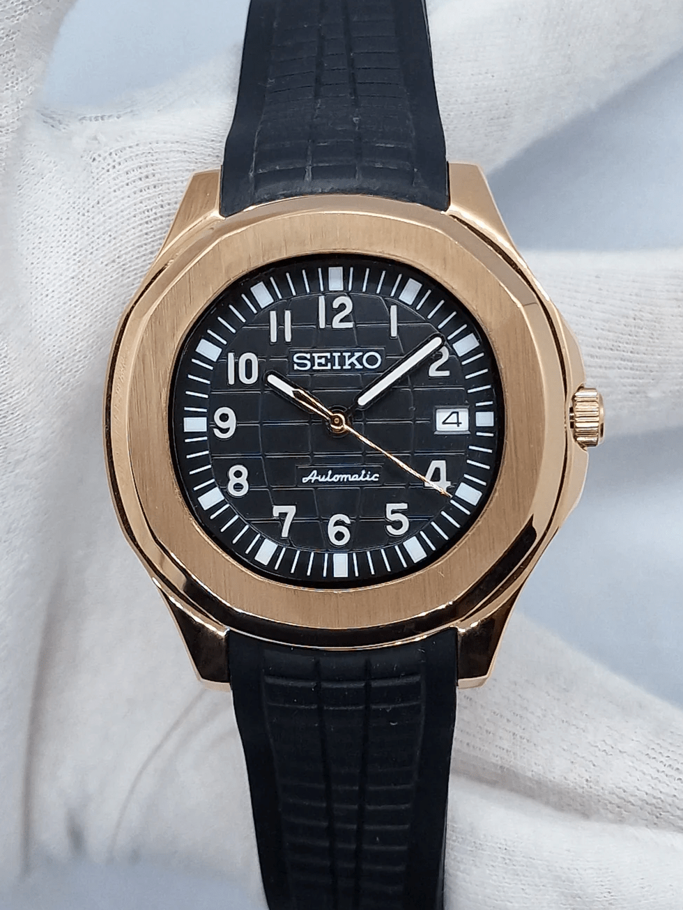 Montre automatique ModTime de style Aquanaut — configuration aux tons or rose (NH35), cadran noir, chiffres blancs, vue de face tenue dans un gant