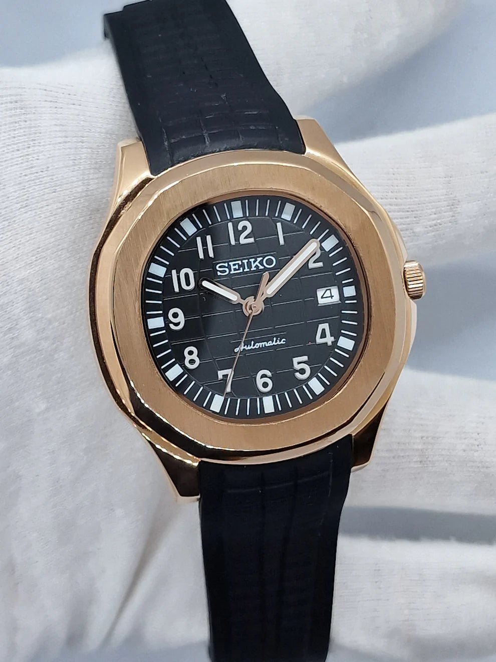 Montre automatique ModTime de style Aquanaut — configuration aux tons or rose (NH35), cadran noir, texture quadrillée, vue en biais tenue dans un gant