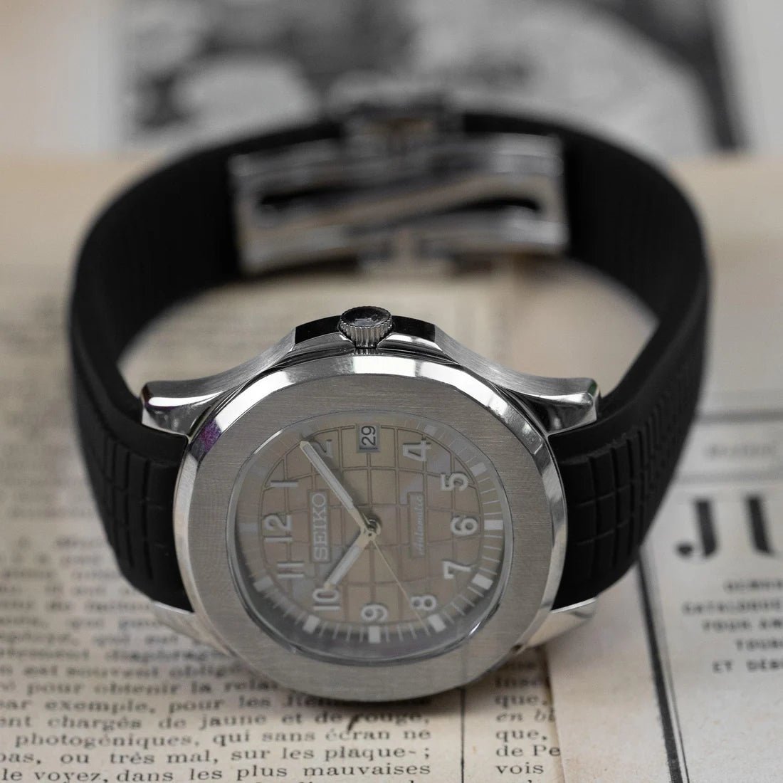 Montre automatique ModTime de style Aquanaut — configuration «Silver Back» (NH35), bracelet noir, couronne au-dessus du cadran, sur le côté sur un journal