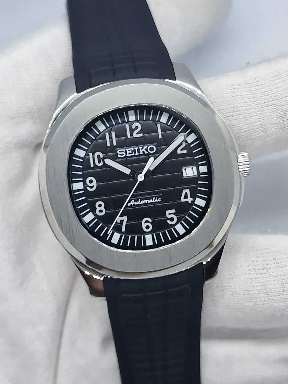 Montre automatique de style Aquanaut — configuration argentée, cadran noir (NH35) avec bracelet noir et chiffres blancs, vue de face tenue en main