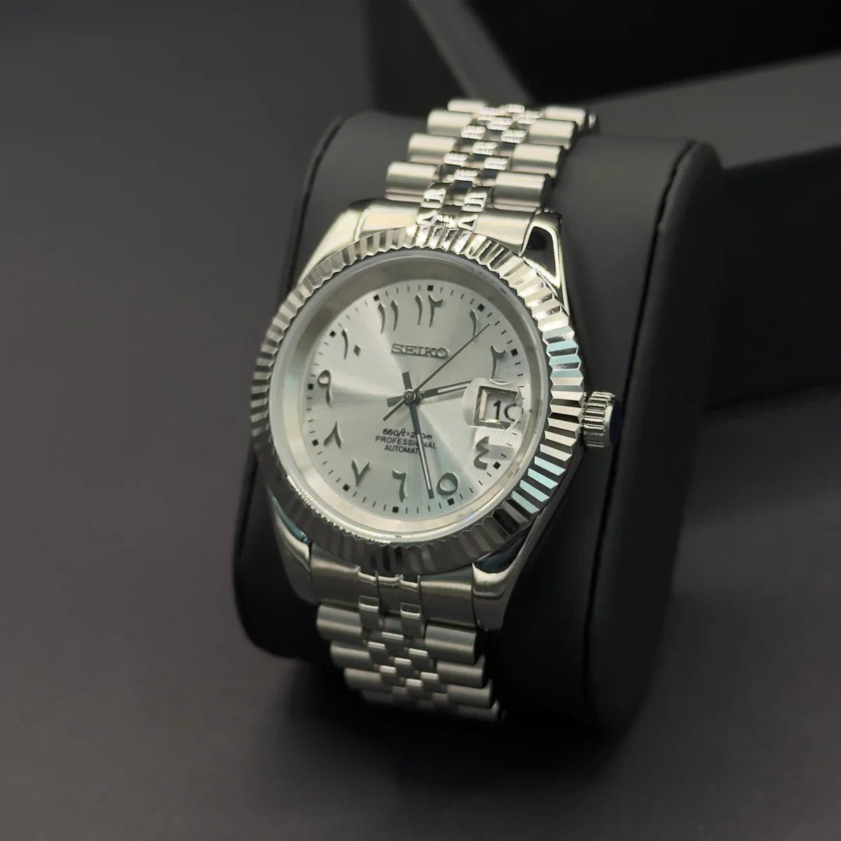 Montre automatique de style Datejust — configuration cadran argenté à chiffres arabes (NH35) avec couronne striée aux tons argentés, vue en biais côté droit sur un coussin