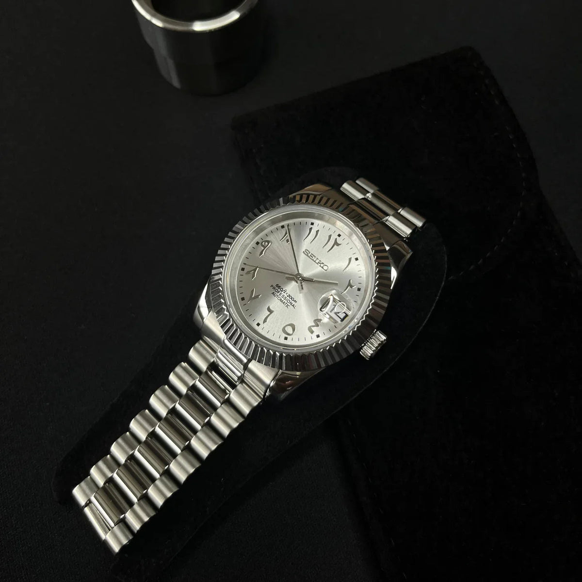 Montre automatique de style Datejust — configuration cadran argenté à chiffres arabes (NH35) avec chiffres aux tons argentés, en diagonale sur une pochette sombre