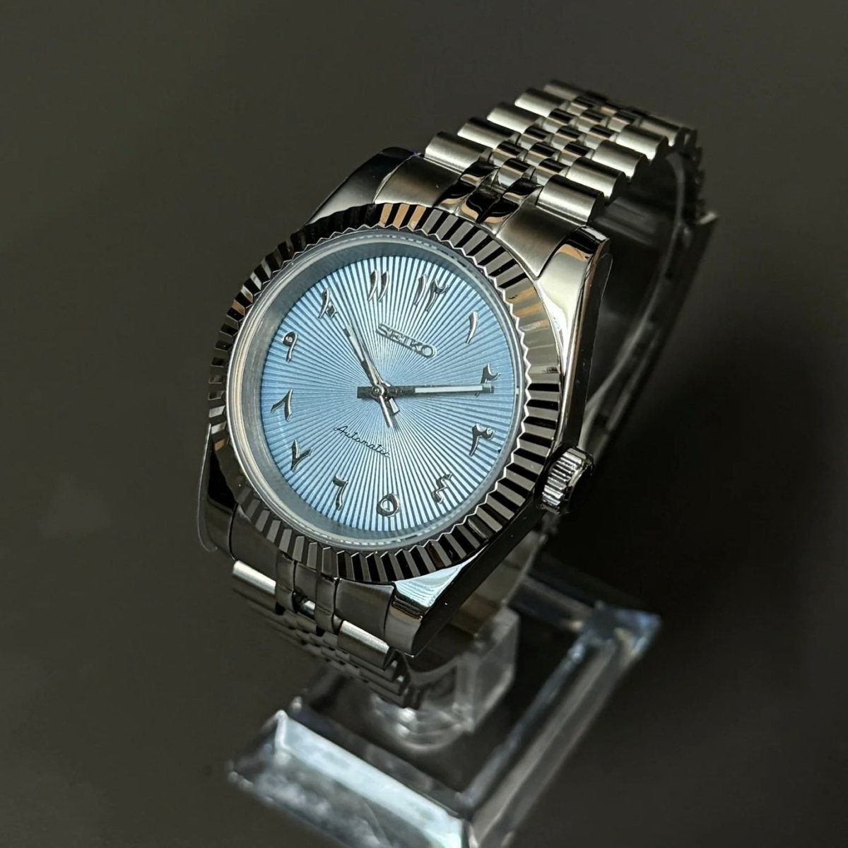 Montre automatique ModTime de style Datejust — configuration argentée et bleu clair, à chiffres arabes (NH35), cadran bleu clair, couronne, vue en biais côté droit sur un support