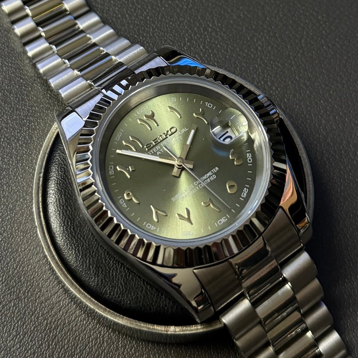 Montre automatique de style Datejust — configuration cadran vert olive à chiffres arabes (NH35) avec aiguilles fines aux tons argentés, sur un support rond
