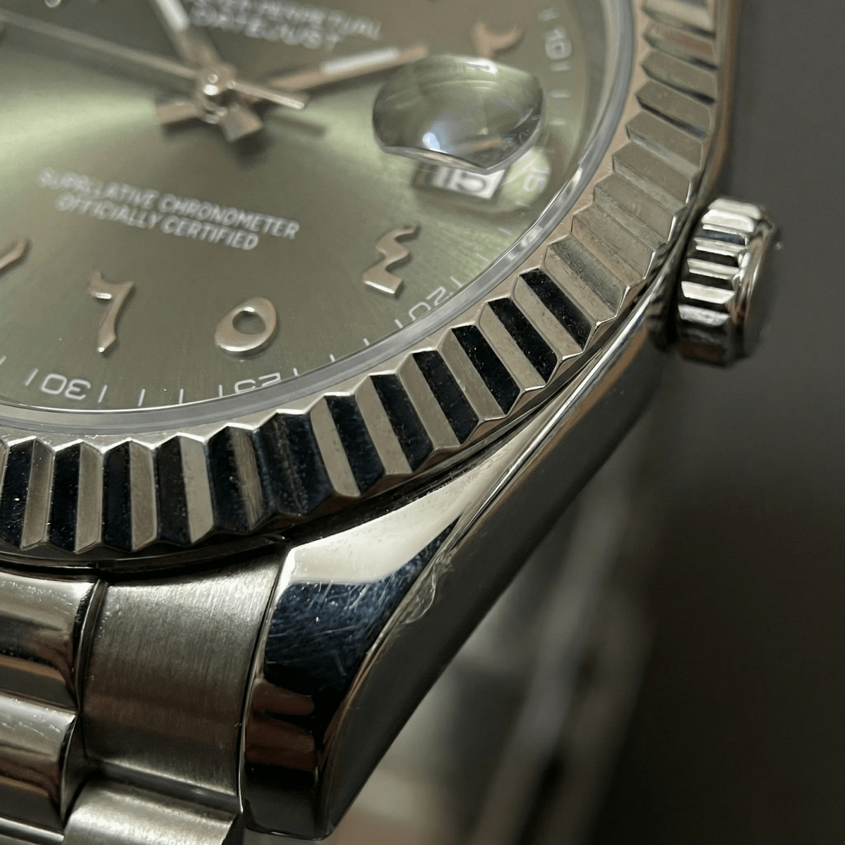Montre automatique de style Datejust — configuration cadran vert olive à chiffres arabes (NH35) avec stries de la lunette aux tons argentés, vue macro côté couronne