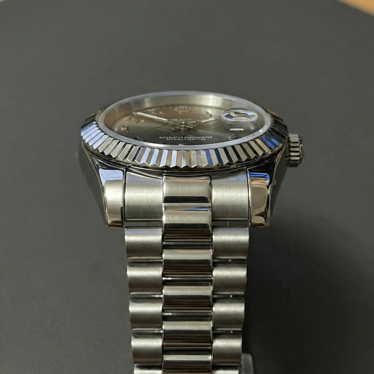 Montre automatique de style Datejust — configuration cadran vert olive à chiffres arabes (NH35) avec maillons centraux aux tons argentés, vue frontale depuis un angle bas