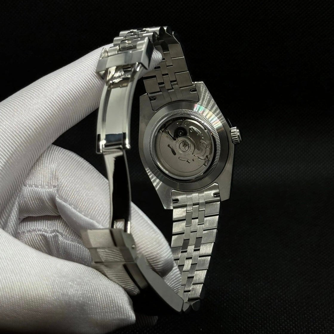 Montre automatique ModTime de style Datejust — configuration argentée et blanche, à chiffres arabes (NH35), bracelet aux tons argentés, fond de boîtier transparent, vue arrière tenue dans une main gantée