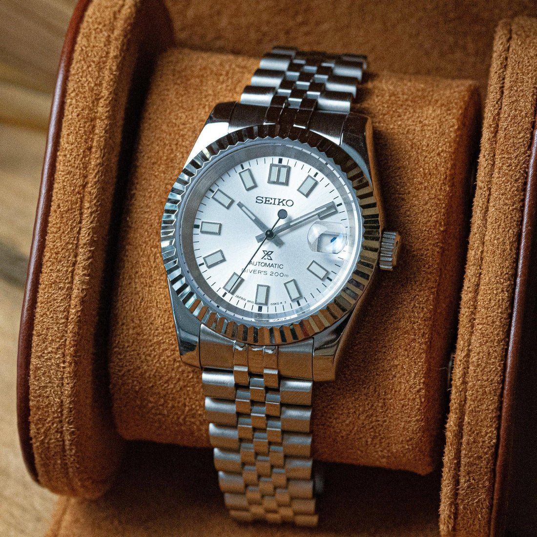 Fiche du modèle ModTime de style Datejust — configuration argentée et blanche (NH35) : cadran blanc portant l'inscription 6R35, vue en biais dans un étui beige