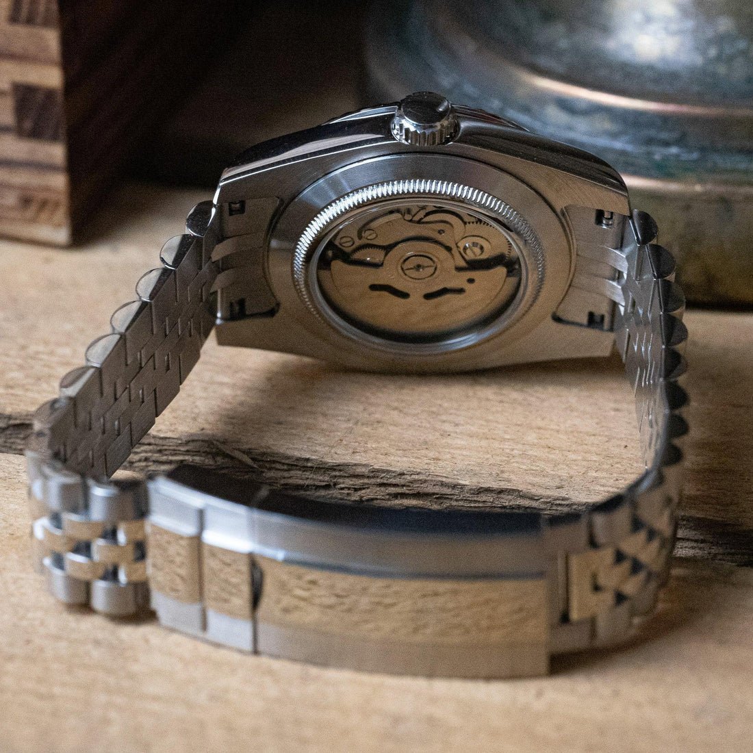 Montre automatique de style Datejust — configuration argentée, cadran blanc (NH35) avec boîtier aux tons argentés, fond transparent, vue arrière sur du bois