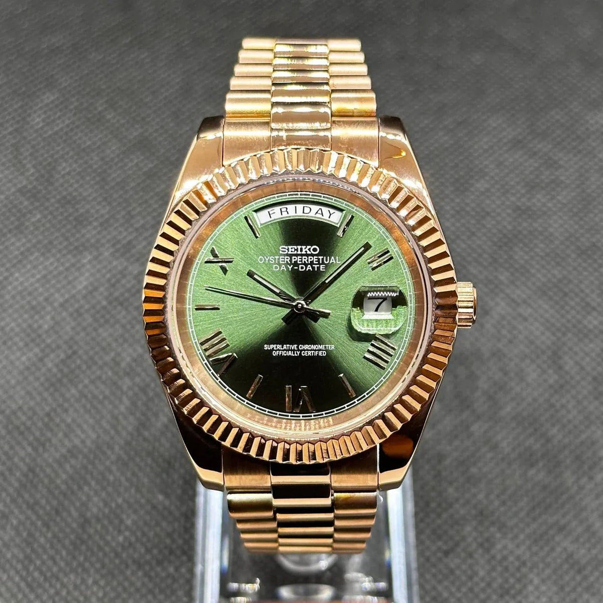 Montre ModTime de style Daydate — configuration aux tons or rose et olive (Miyota 8285), cadran olive soleillé, chiffres romains, vue de face sur un support