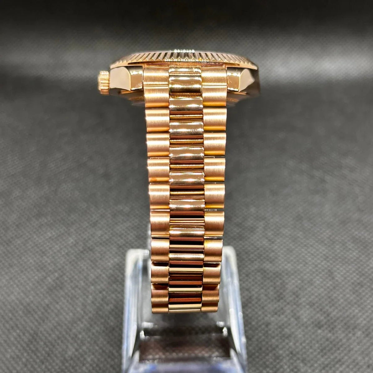 Montre ModTime de style Daydate — configuration aux tons or rose et olive (Miyota 8285), bracelet aux tons rosés, maillons centraux polis, vue de côté sur un support