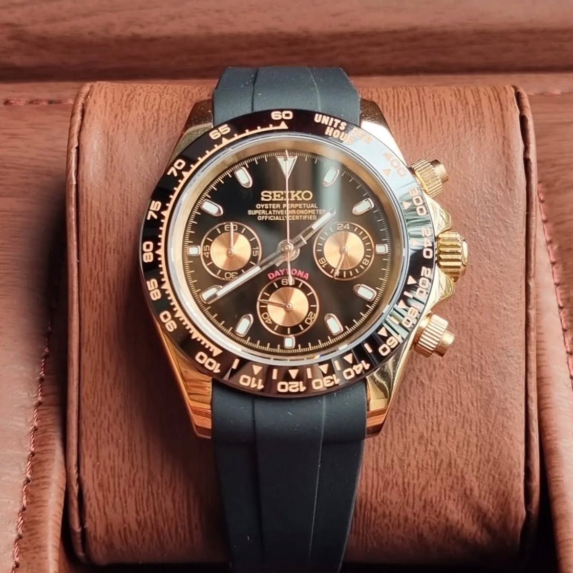 Chronographe méca-quartz ModTime de style Daytona — configuration aux tons or rose et noirs (VK63), bracelet noir, index triangulaire supérieur, sur un rouleau