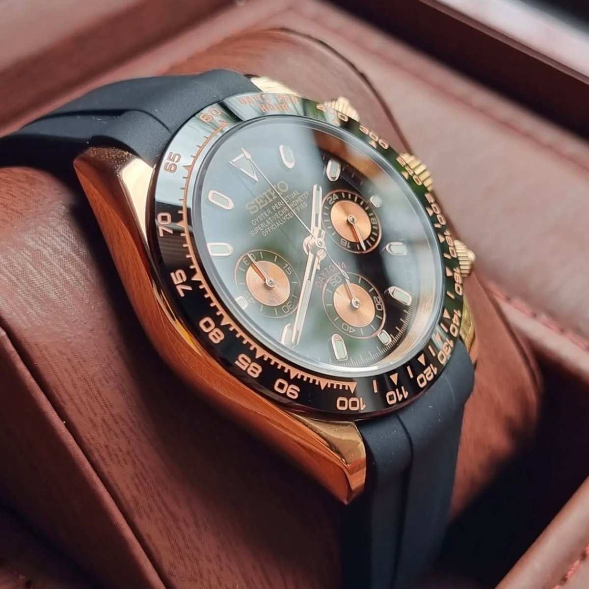 Chronographe méca-quartz ModTime de style Daytona — configuration aux tons or rose et noirs (VK63), cadran noir, flanc du boîtier poli, vue depuis un angle bas