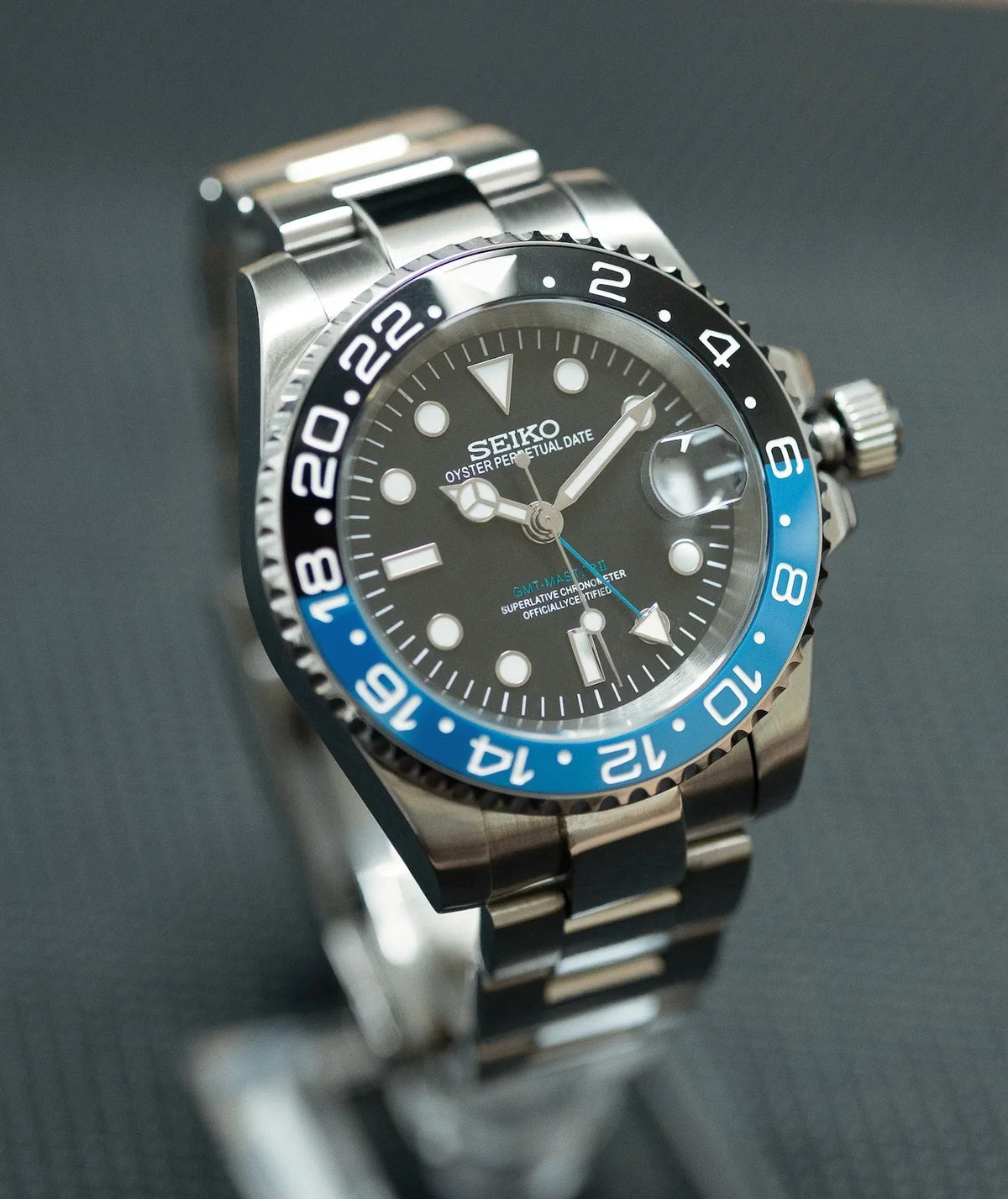 Montre automatique GMT — configuration «Batman» (NH34) avec cadran noir et aiguille GMT bleue, vue en biais du côté gauche
