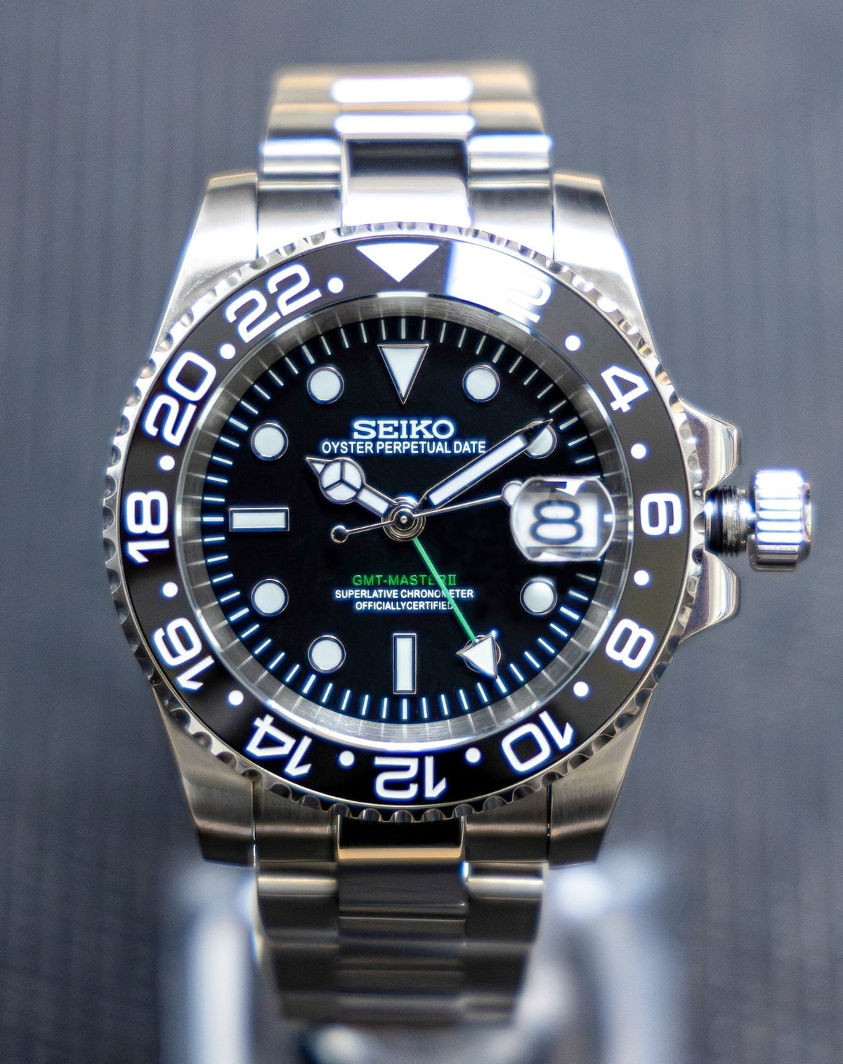 Montre automatique GMT — configuration noire (NH34) avec cadran noir et aiguille GMT verte, gros plan frontal