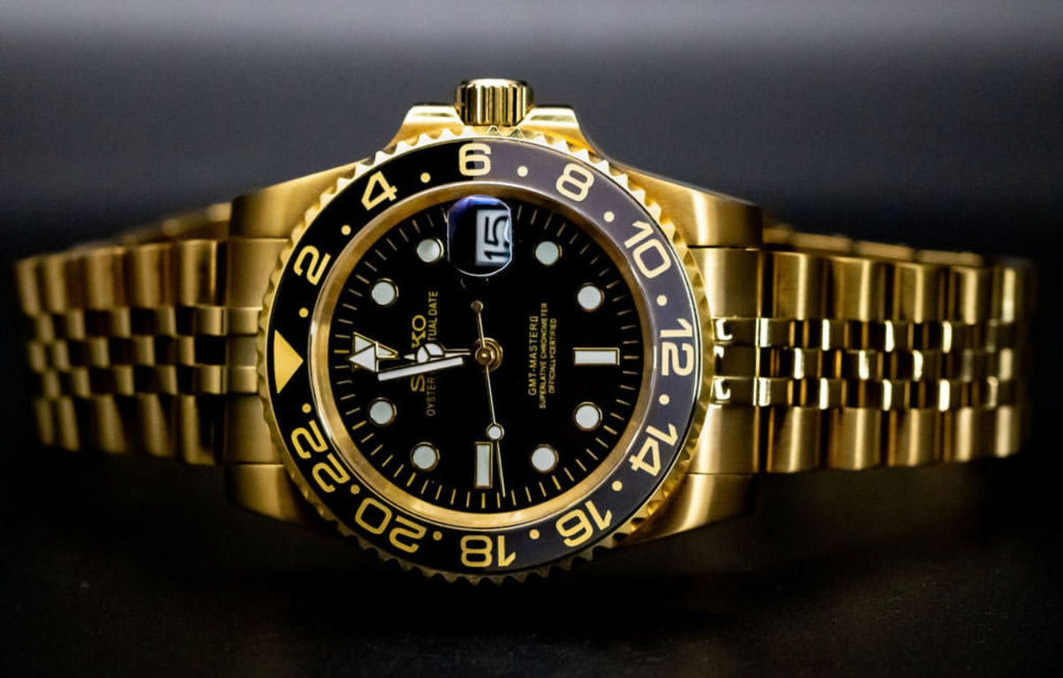 Montre automatique GMT — configuration aux tons dorés et noirs (NH34) avec cadran noir et maillons de style Jubilee aux tons dorés, vue de face horizontale