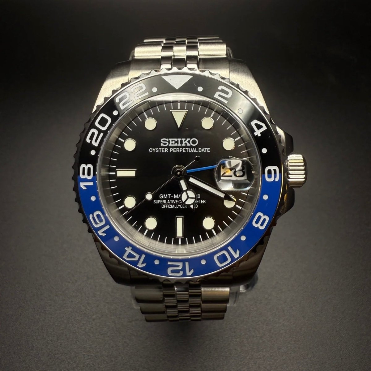 Montre automatique GMT — configuration «Batgirl» (NH34) avec cadran noir et aiguille GMT bleue, vue rapprochée de face