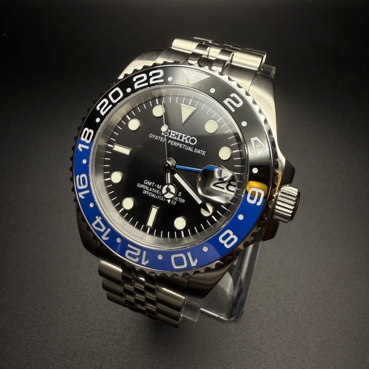 Montre automatique GMT — configuration «Batgirl» (NH34) avec lunette bleue et noire et couronne striée, vue en biais du côté droit
