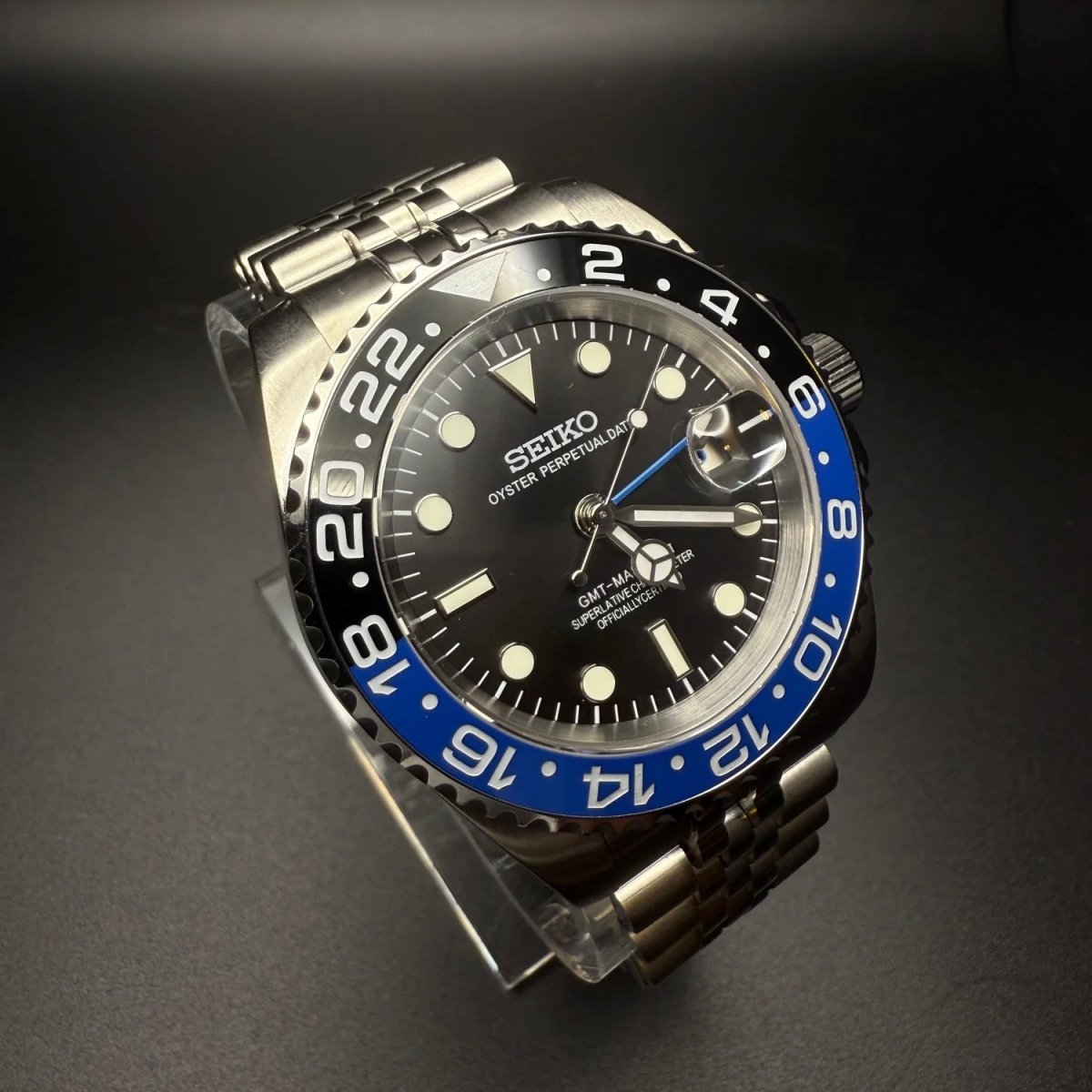 Montre automatique GMT — configuration «Batgirl» (NH34) avec cadran noir et loupe de date surélevée, vue en biais du côté gauche