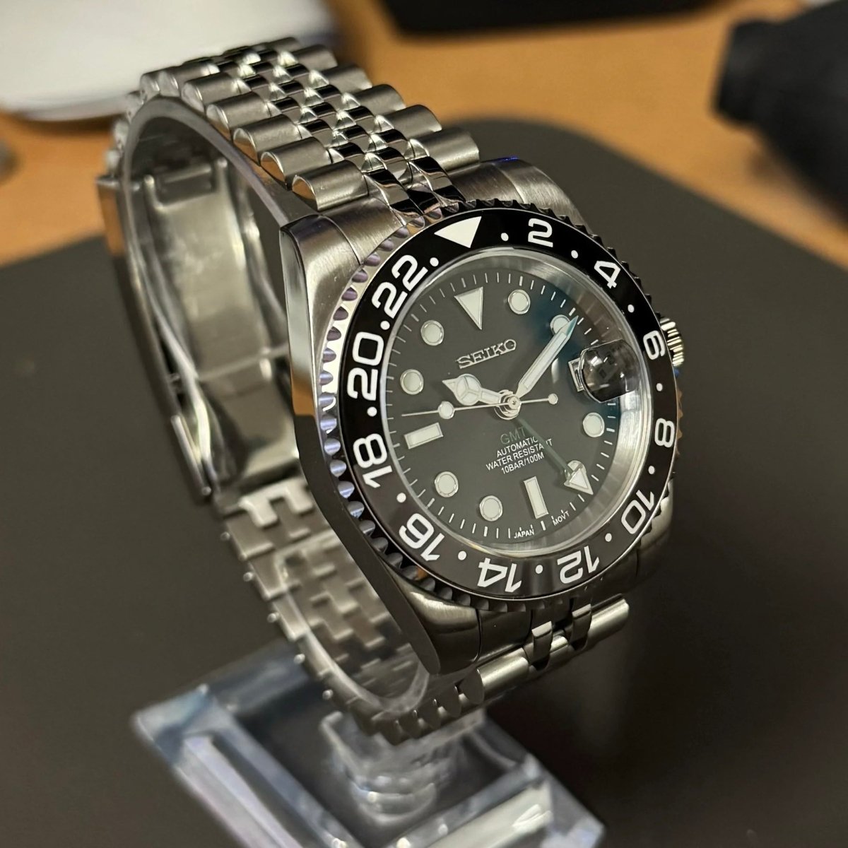 Montre automatique GMT — configuration «Bruce Wayne» (NH34) avec bracelet de style Jubilee aux tons argentés et loupe de date, vue en biais du côté gauche