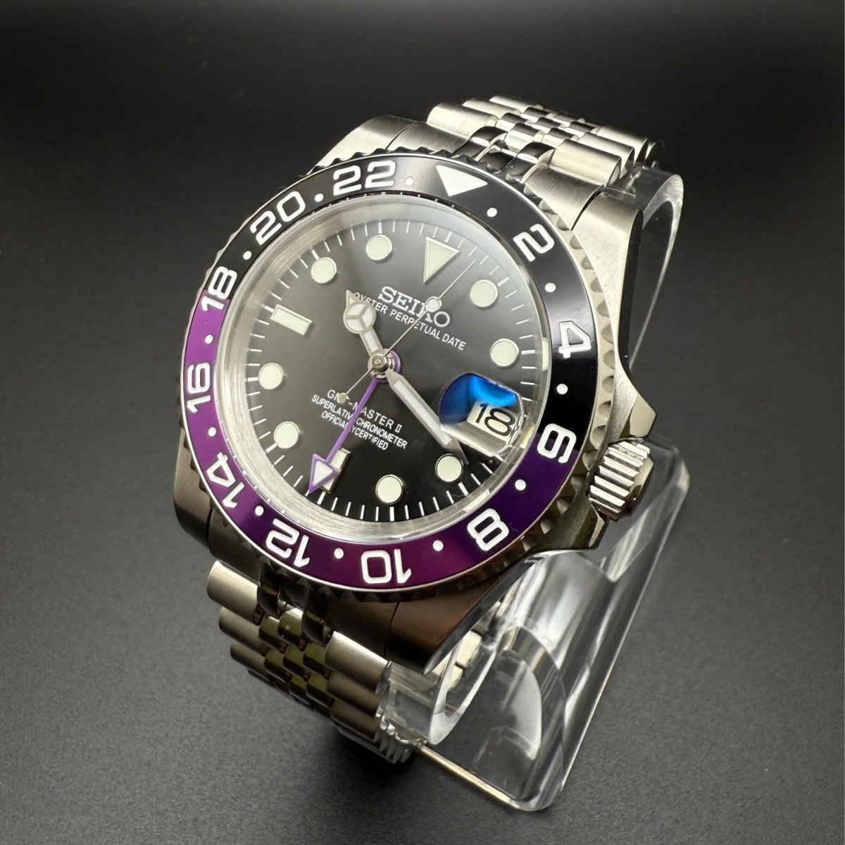 Montre automatique GMT — configuration «Joker» (NH34) avec lunette violette et noire et couronne striée, vue en biais du côté droit