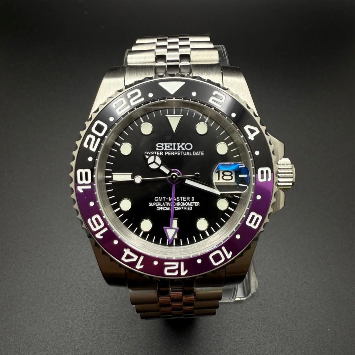 Montre automatique GMT — configuration «Joker» (NH34) avec cadran noir et aiguille GMT violette, vue rapprochée de face