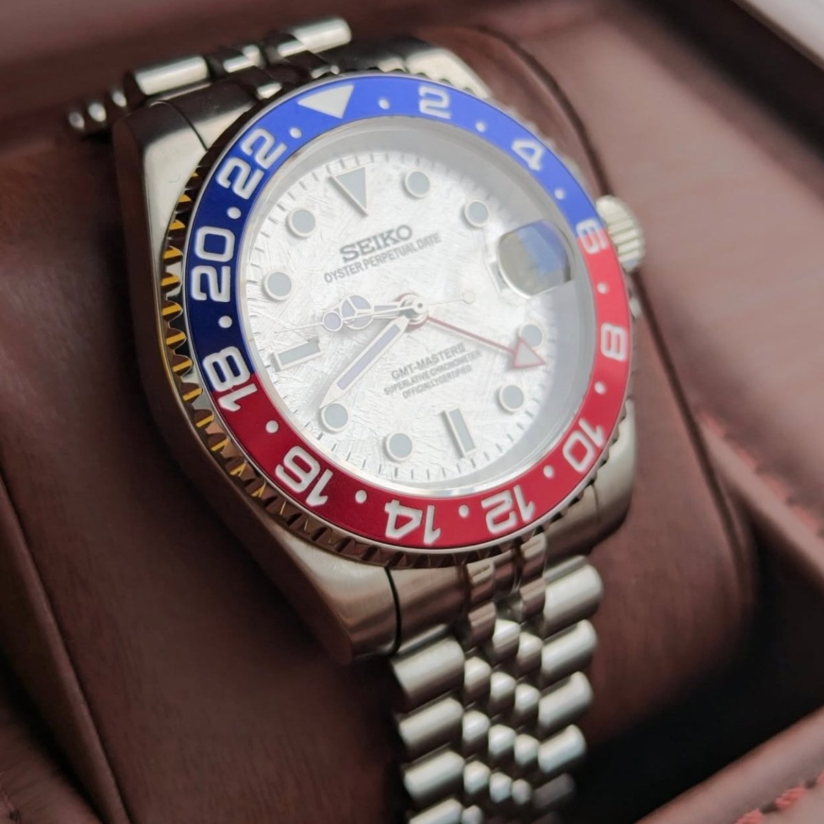 Montre automatique GMT — configuration «Meteorite» (NH34) avec lunette rouge et bleue et cadran à motif, gros plan oblique
