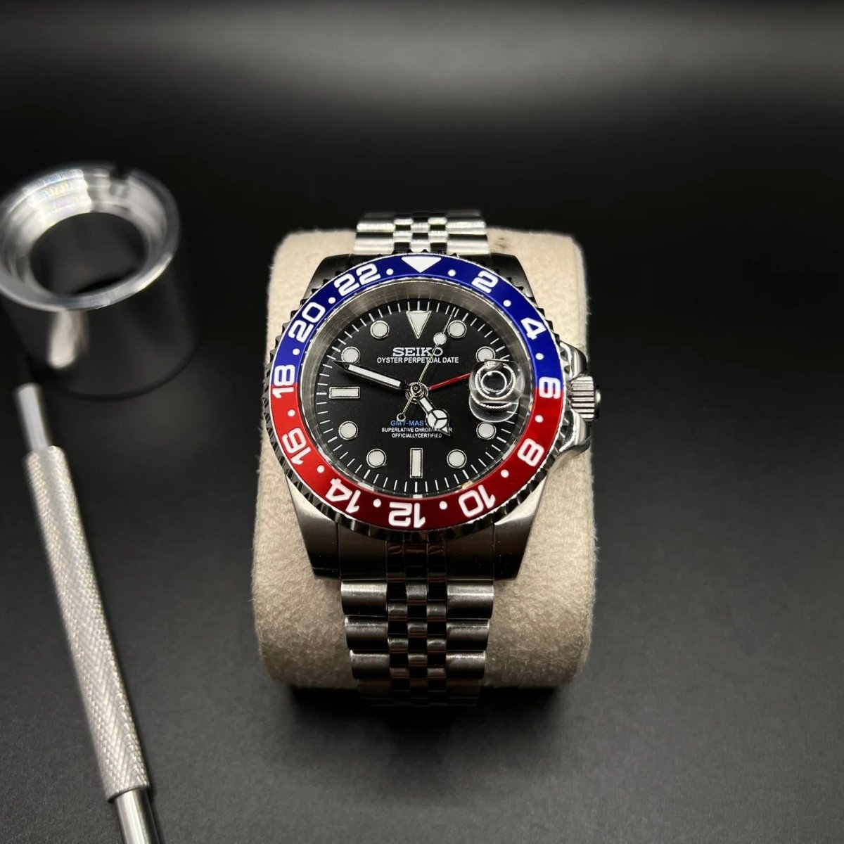 Montre automatique GMT — configuration «Pepsi» (NH34) avec une lunette rouge et bleue et un bracelet de style Jubilee sur un coussin à côté d'outils