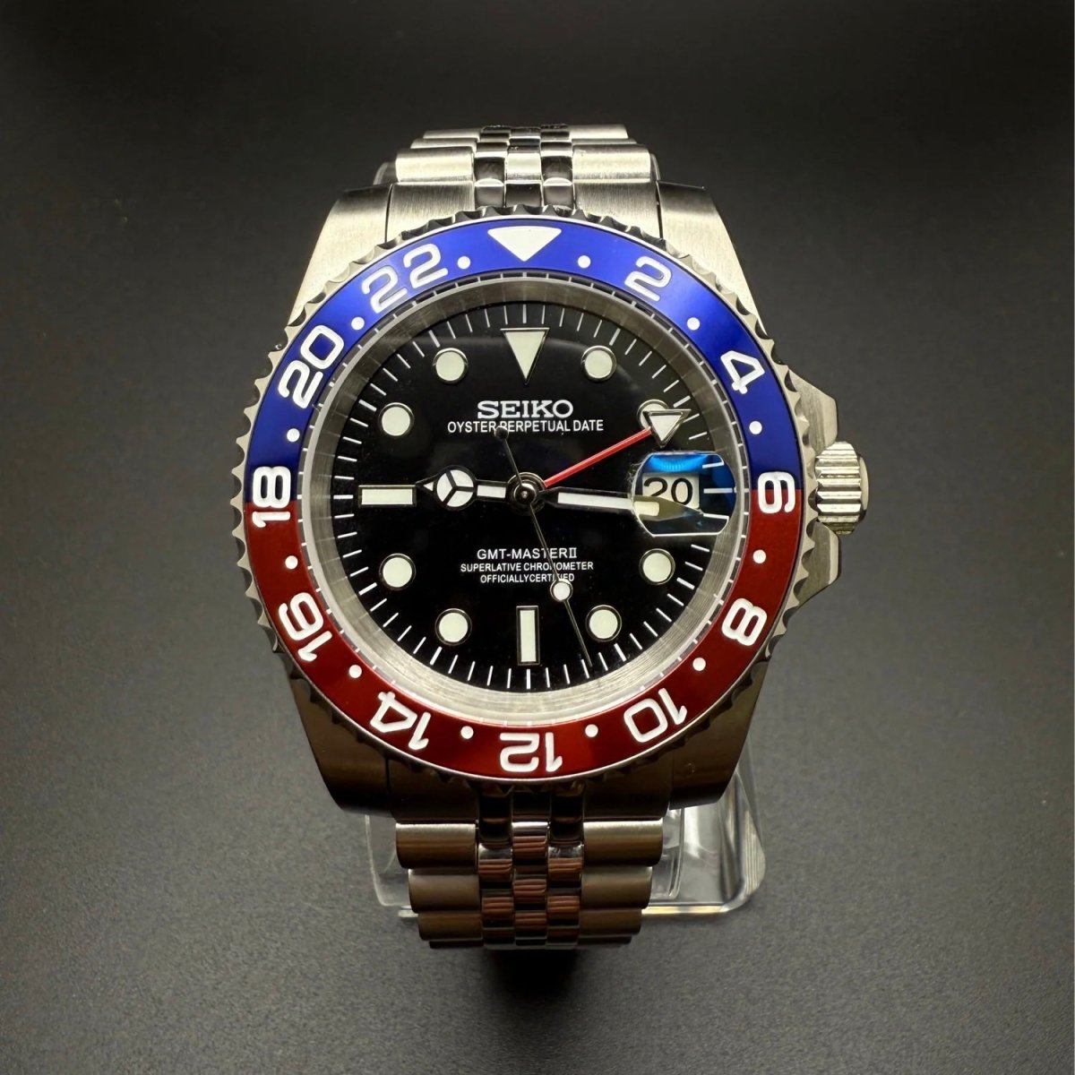 Montre automatique GMT — configuration «Pepsi» (NH34) avec cadran noir, aiguille GMT rouge et bracelet de style Jubilee, vue rapprochée de face