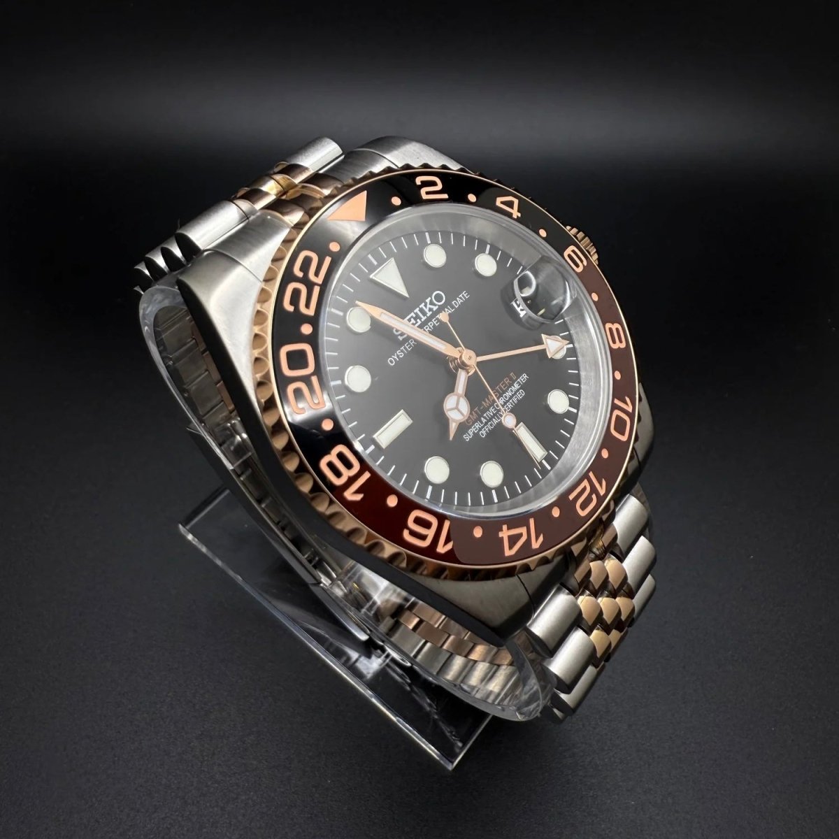 Montre automatique GMT — configuration «Root Beer», bicolore (NH34) avec lunette marron et noire et chiffres aux tons dorés, vue de trois quarts côté gauche