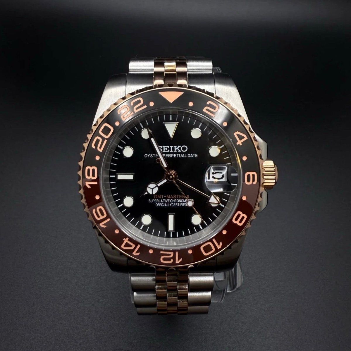 Montre automatique GMT — configuration «Root Beer», bicolore (NH34) avec cadran noir et aiguilles aux tons dorés, gros plan de face