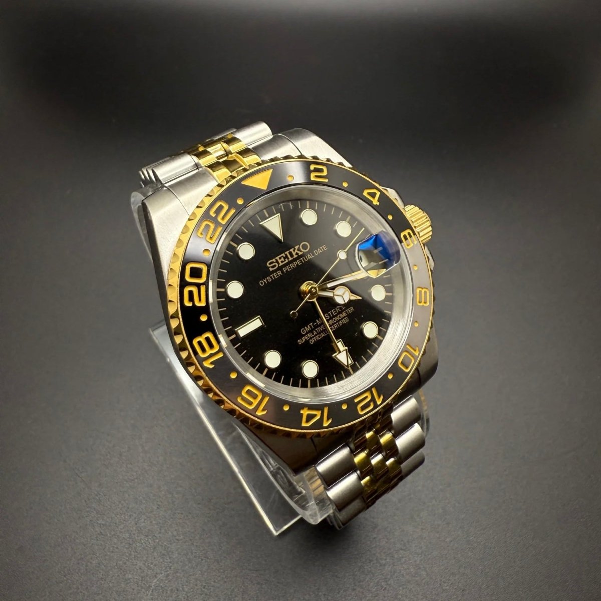 Montre automatique GMT — configuration bicolore et noire (NH34) avec lunette noire et maillons de style Jubilee, vue en biais du côté gauche