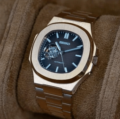 Montre automatique de style Nautilus — configuration chocolat, cœur ouvert (NH38) avec lunette aux tons or rose, inclinée sur un coussin