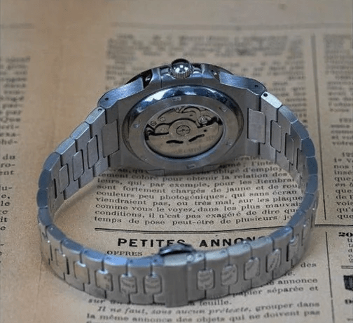 Montre automatique de style Nautilus — configuration cadran argenté (NH35) avec boîtier aux tons argentés, fond transparent, vue arrière sur du papier