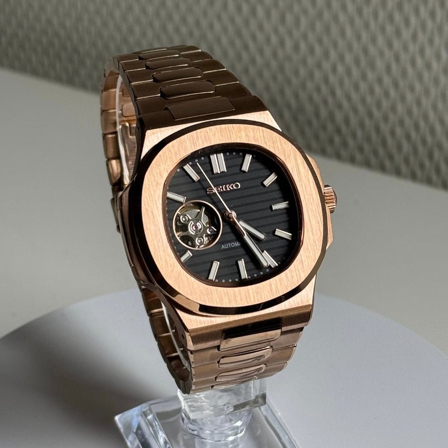 Montre automatique ModTime de style Nautilus — configuration aux tons or rose et noirs, cœur ouvert (NH38), cadran noir, balancier visible, vue en biais côté droit