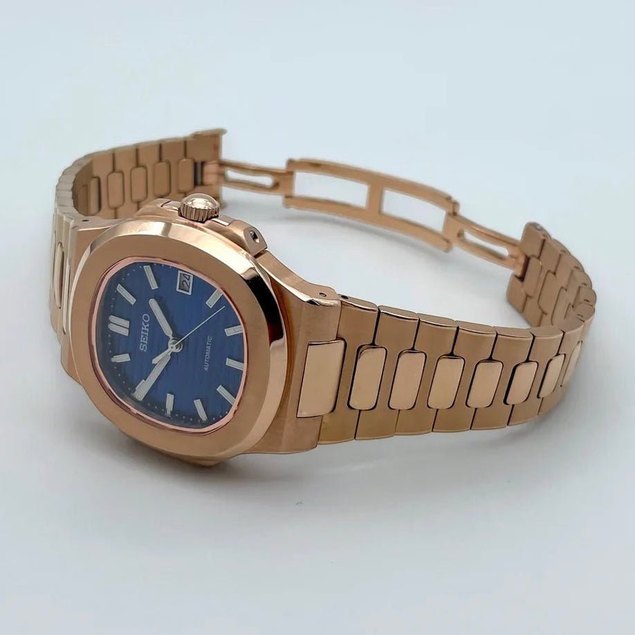 Montre automatique de style Nautilus — configuration cadran bleu (NH35) avec maillons aux tons or rose, fermoir ouvert, posée sur le côté