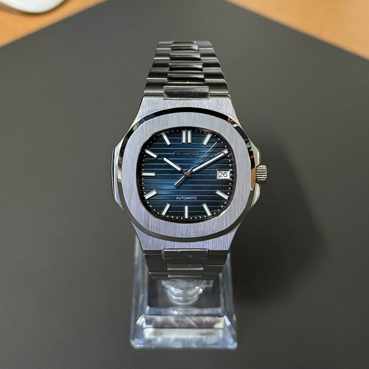 Montre automatique de style Nautilus — configuration argentée, cadran bleu (NH35) avec cadran bleu, lunette brossée, vue de face sur un support