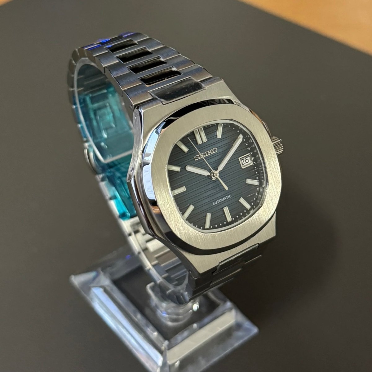 Montre automatique de style Nautilus — configuration argentée, cadran bleu (NH35) avec maillons aux tons argentés, cadran rayé, vue en biais côté gauche