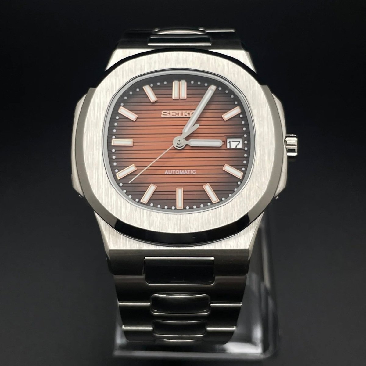 Montre automatique de style Nautilus — configuration argentée, cadran rouge cerise (NH35) avec boîtier aux tons argentés, cadran rayé, vue de face sur un support