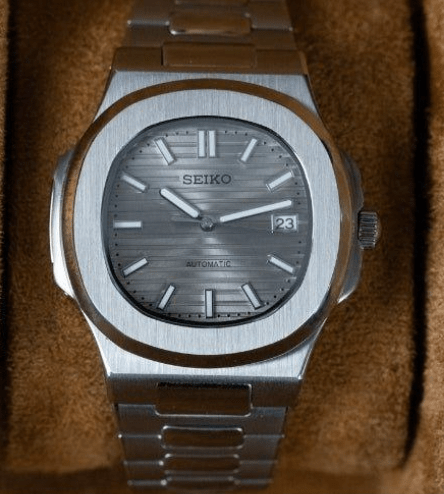 Montre automatique de style Nautilus — configuration cadran argenté (NH35) avec boîtier aux tons argentés, guichet de date, vue de face sur un coussin
