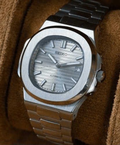 Montre automatique de style Nautilus — configuration cadran argenté (NH35) avec boîtier aux tons argentés, couronne striée, en biais sur un coussin