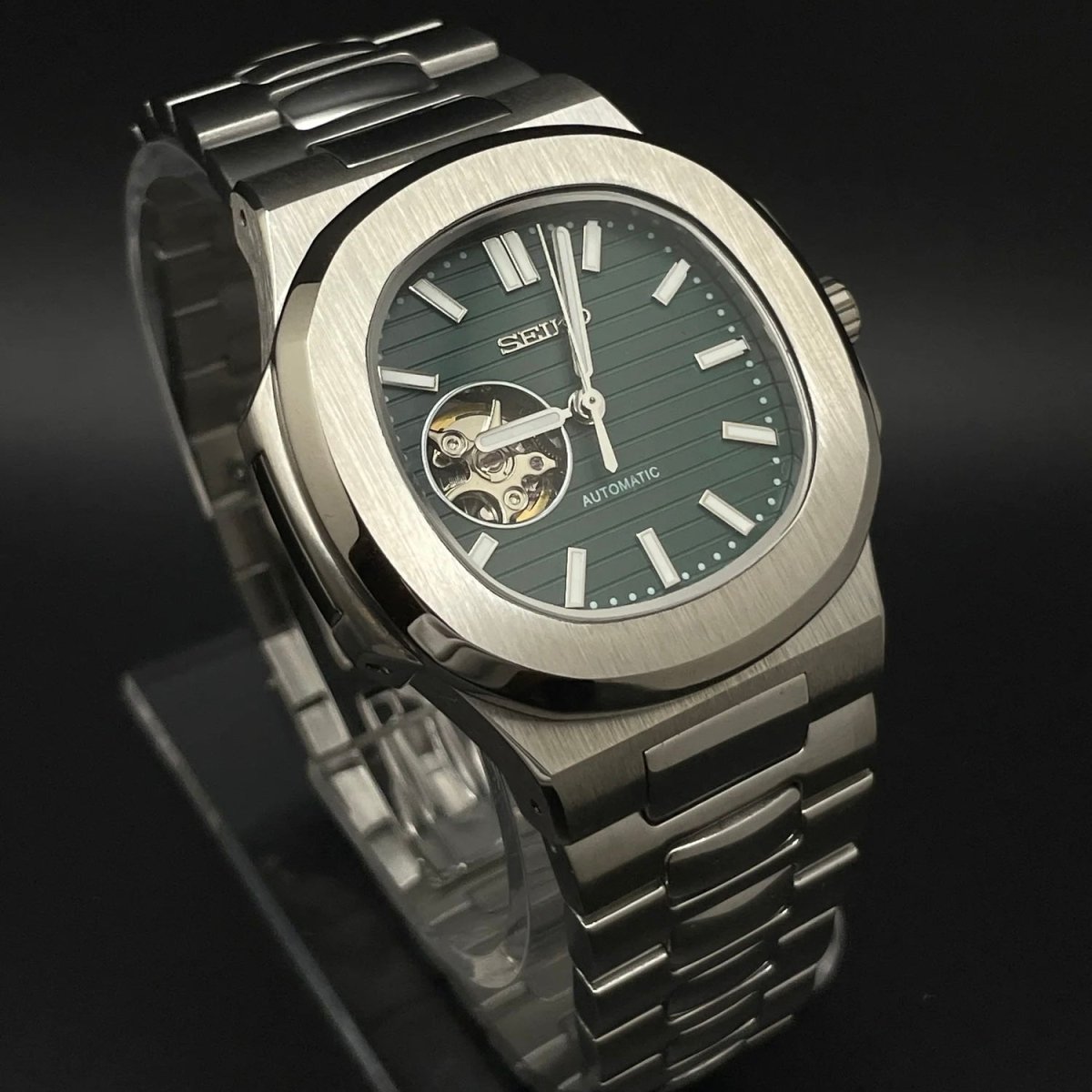 Montre automatique de style Nautilus — configuration vert olive, cœur ouvert (NH38) avec boîtier aux tons argentés, index bâtons, vue en biais côté gauche