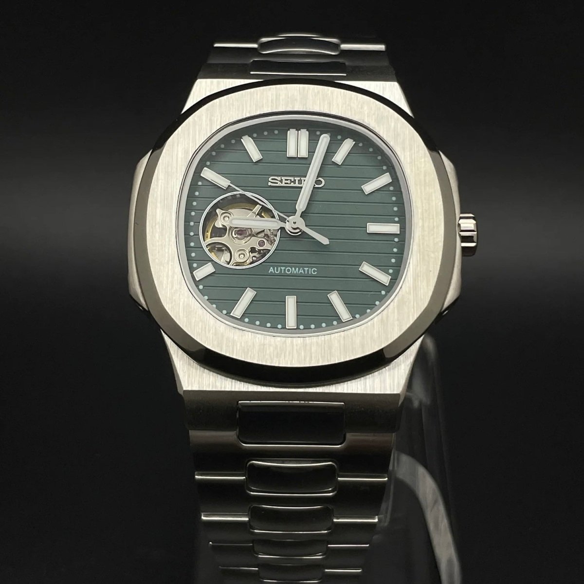 Montre automatique de style Nautilus — configuration vert olive, cœur ouvert (NH38) avec boîtier aux tons argentés, lunette brossée, vue de face sur un support