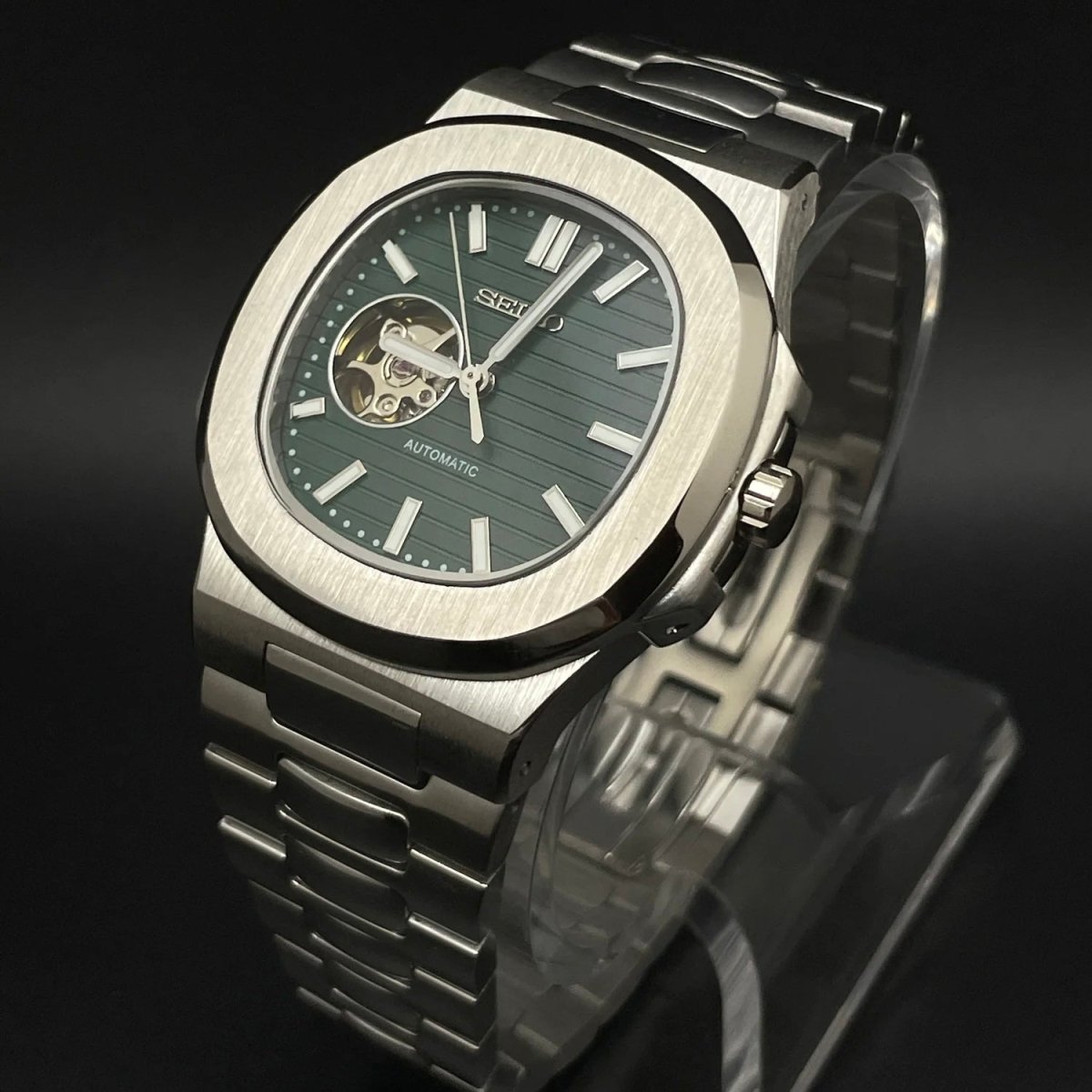 Montre automatique de style Nautilus — configuration vert olive, cœur ouvert (NH38) avec maillons aux tons argentés, ouverture ronde du cadran, vue en biais côté droit