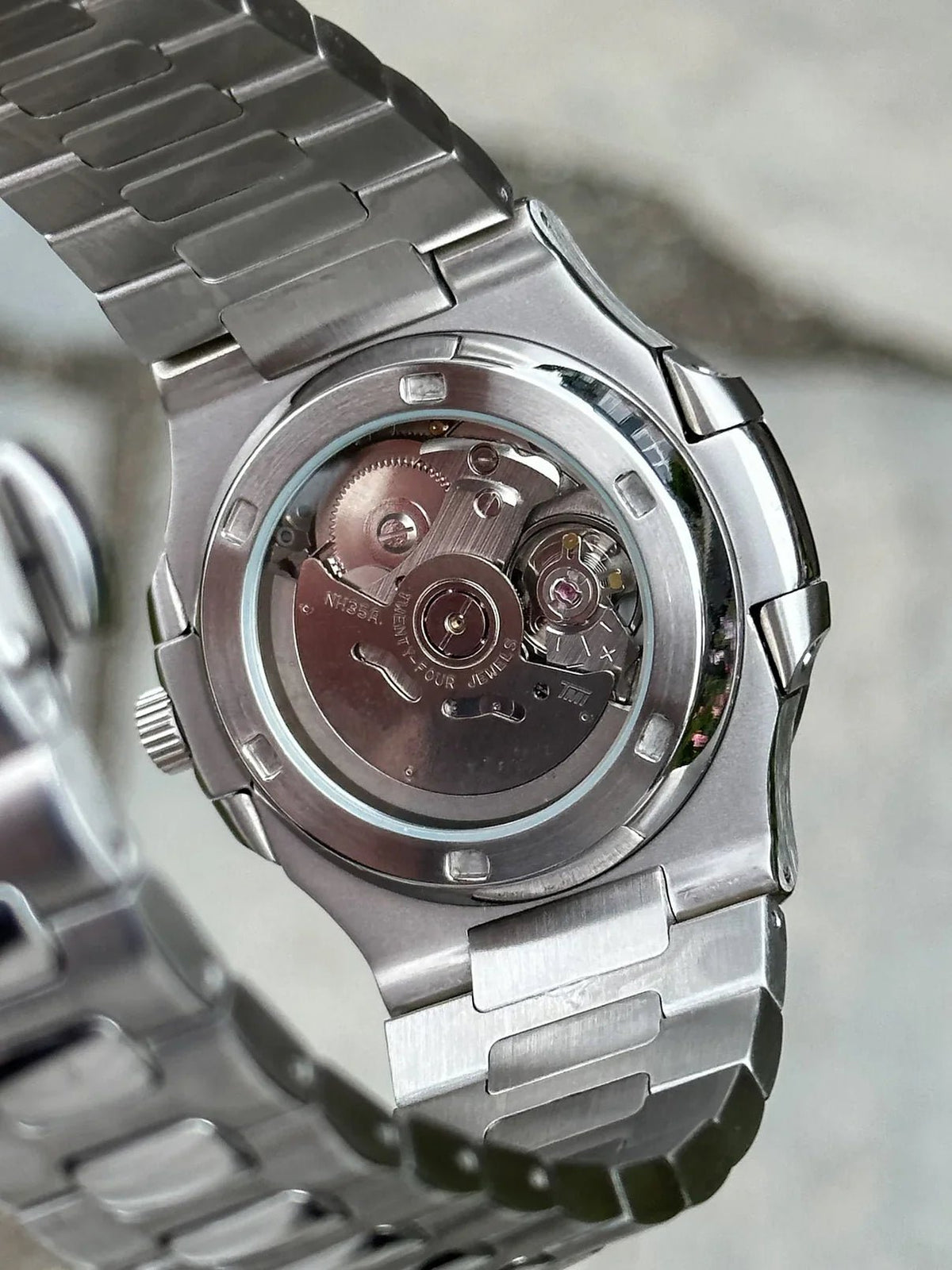 Fiche du modèle ModTime de style Nautilus — configuration argentée, «Tiffany», cœur ouvert (NH38) : fond du boîtier aux tons argentés, rotor portant l'inscription NH35A, gros plan arrière