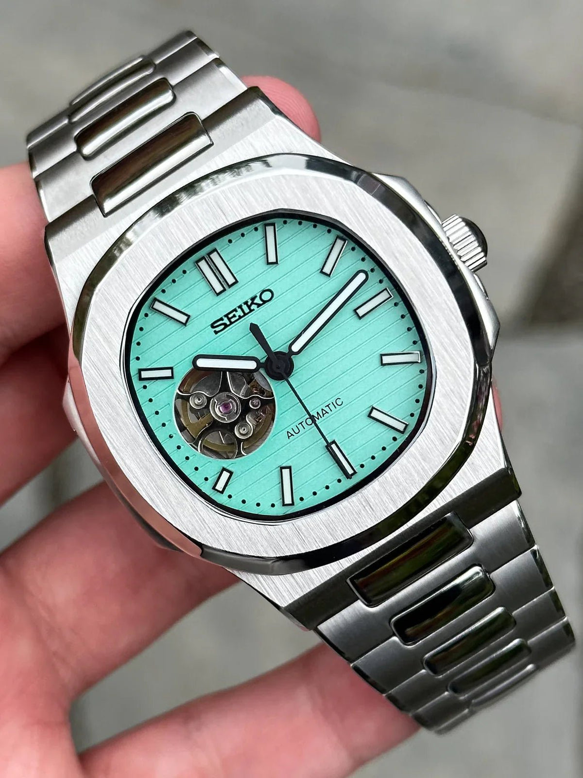 Montre automatique ModTime de style Nautilus — configuration «Tiffany», cœur ouvert (NH38), cadran turquoise, balancier visible, vue tenue en main